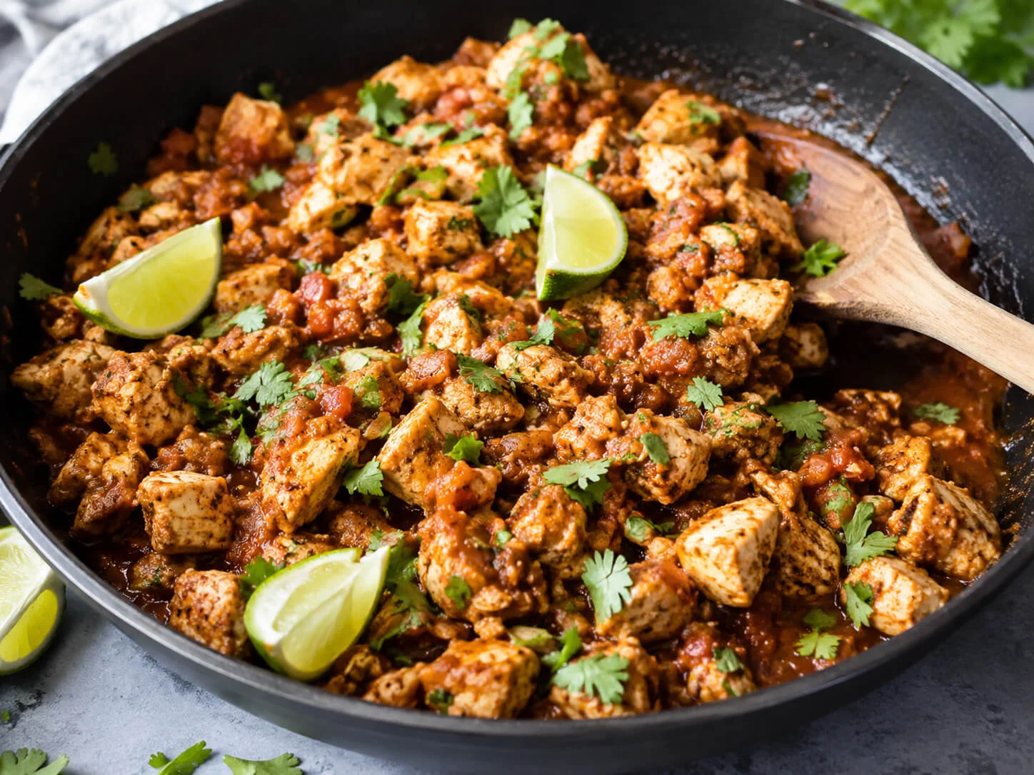 Chicken taco meal prep filling with seasoned chicken, salsa, cilantro, lime, and taco spices in a skillet