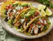 High protein chicken tacos with grilled chicken, black beans, avocado, salsa, Greek yogurt sauce, cilantro, and lime