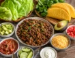 Low carb taco night spread with taco meat, lettuce wraps, cheese shells, avocado, salsa, sour cream, cilantro, and lime